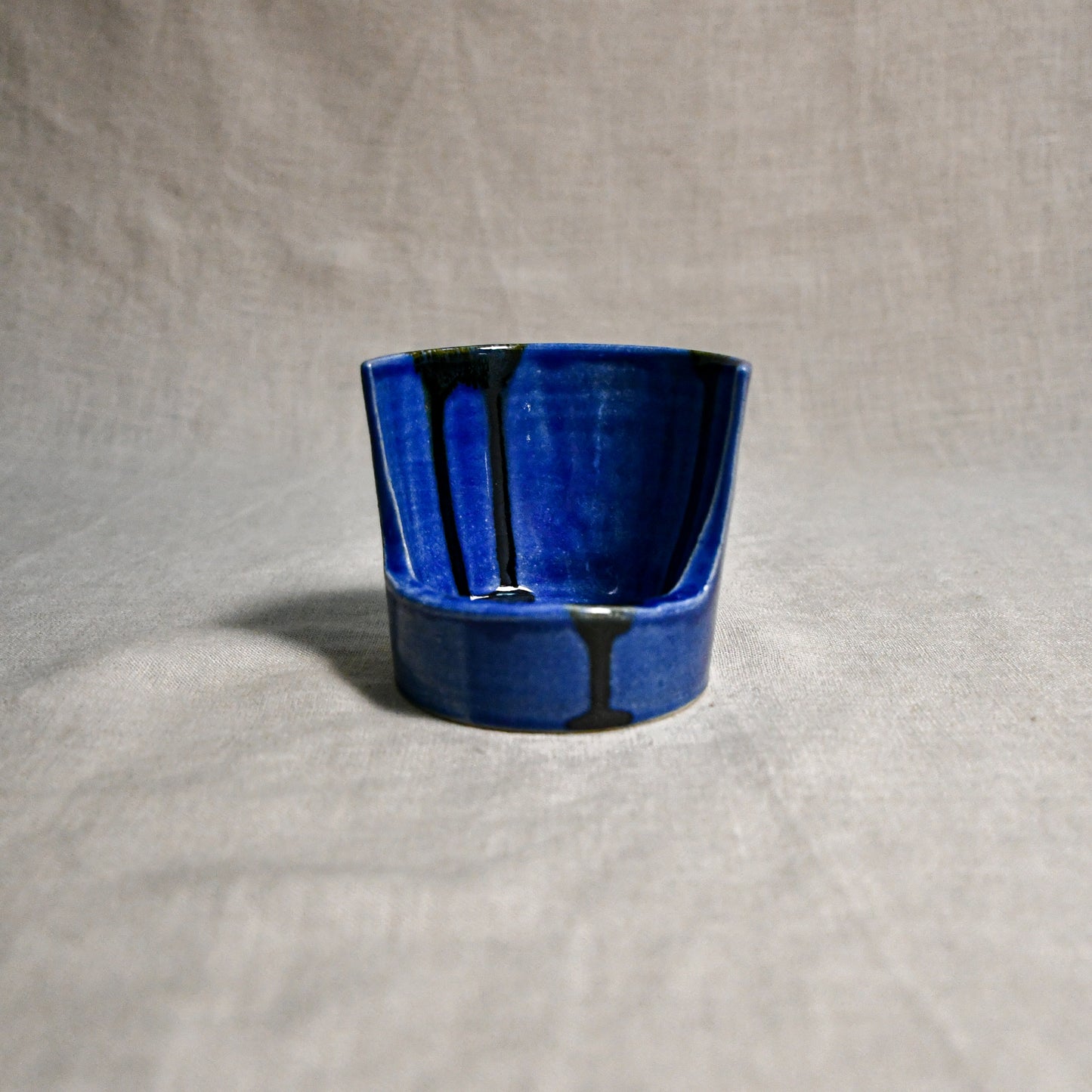 Close up of blue vertical handmade pottery spoon rest from the 5th Buffalo collection by Leigh Art with black drips