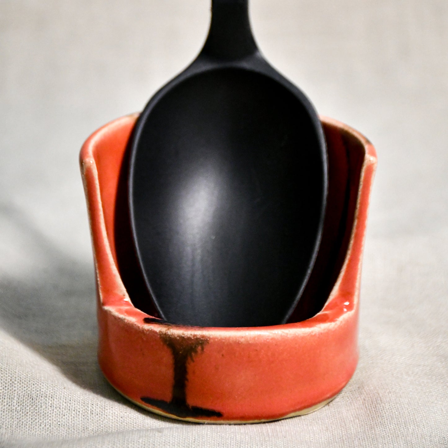 Vertical coral handmade spoon rest with serving spoon from the 5th Buffalo collection by Leigh Art