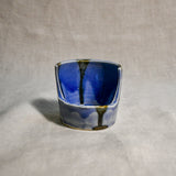 Close up of purple vertical handmade pottery spoon rest from the 5th Buffalo collection by Leigh Art with black drips and crazing
