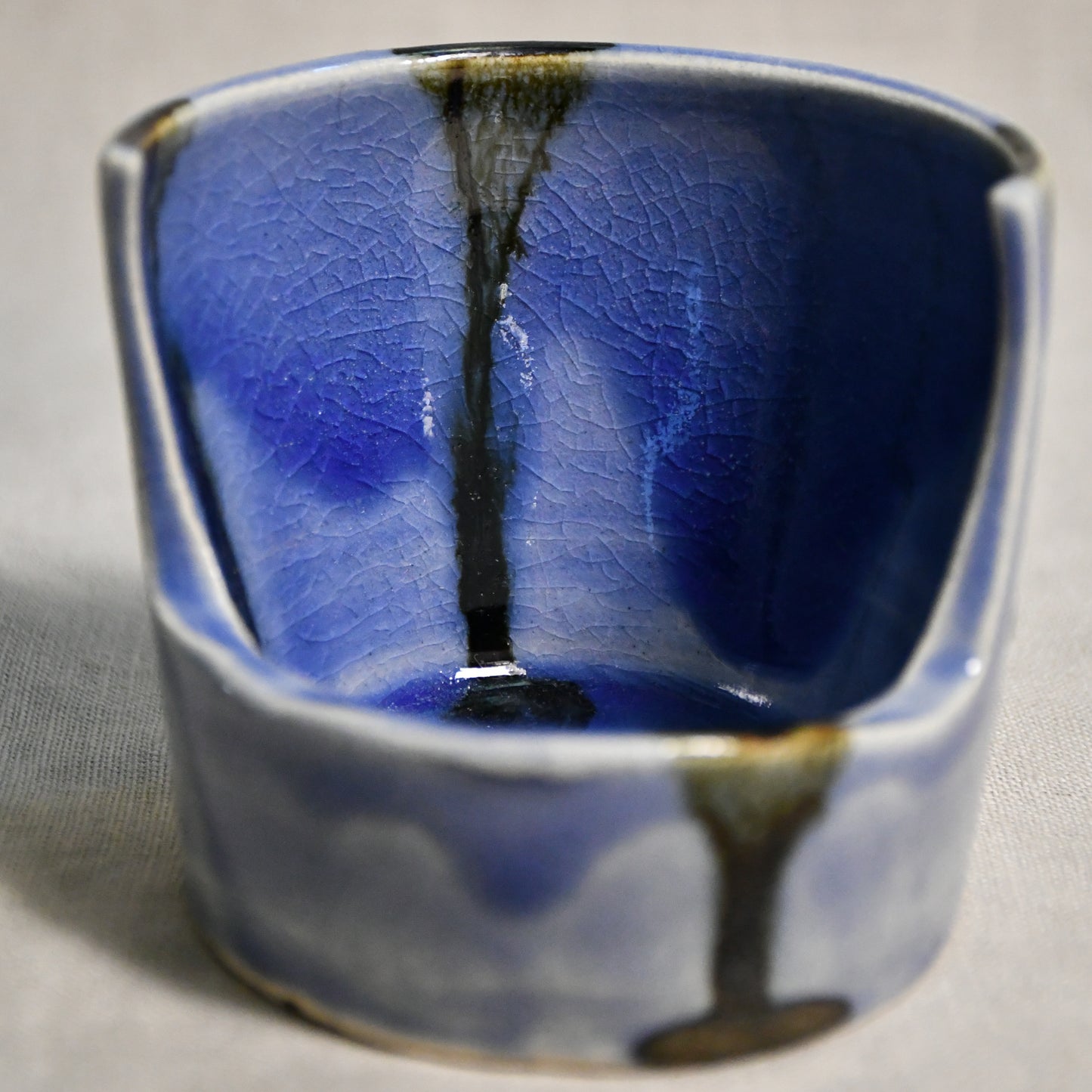 Close up of purple vertical handmade pottery spoon rest from the 5th Buffalo collection by Leigh Art with black drips and crazing