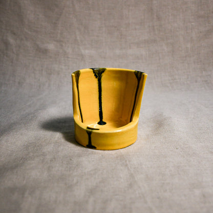 Close up of yellow vertical handmade pottery spoon rest from the 5th Buffalo collection by Leigh Art with black drips 