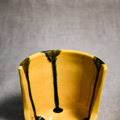 Close up of yellow vertical handmade pottery spoon rest from the 5th Buffalo collection by Leigh Art with black drips and crazing