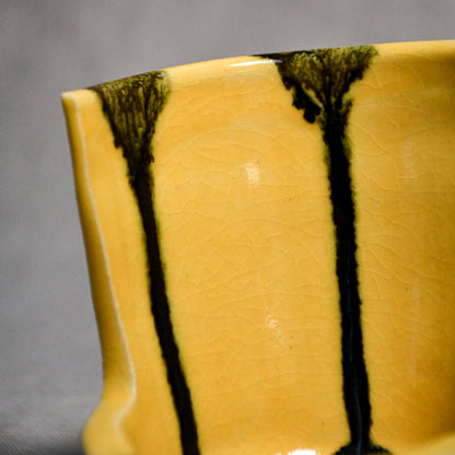 Close up of yellow vertical handmade pottery spoon rest from the 5th Buffalo collection by Leigh Art with black drips and crazing
