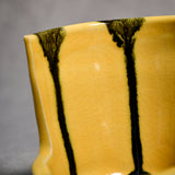 Close up of yellow vertical handmade pottery spoon rest from the 5th Buffalo collection by Leigh Art with black drips and crazing