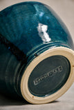 Bottom view of a dark teal ceramic chili bowl showing exposed stoneware clay and kiln marks