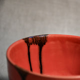 Close-up of black glaze drips on a coral handmade pottery bowl