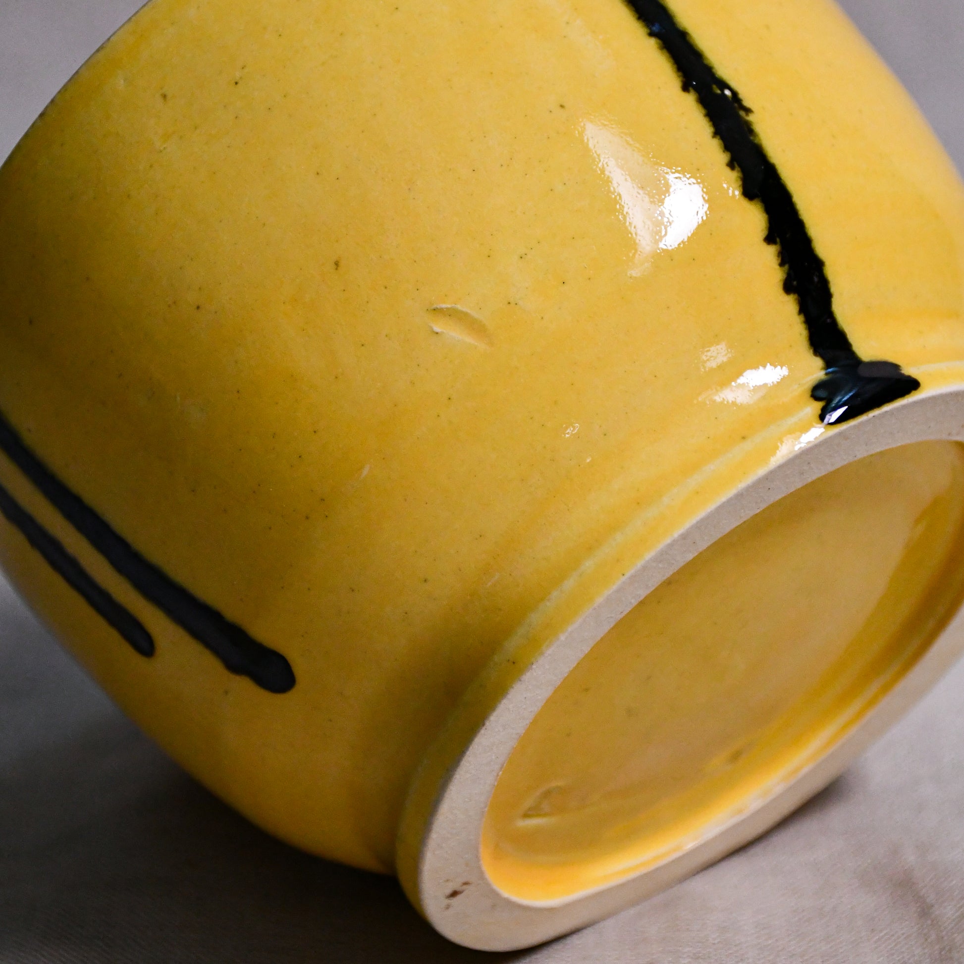 Bottom view of a yellow ceramic chili bowl showing exposed stoneware clay and texture