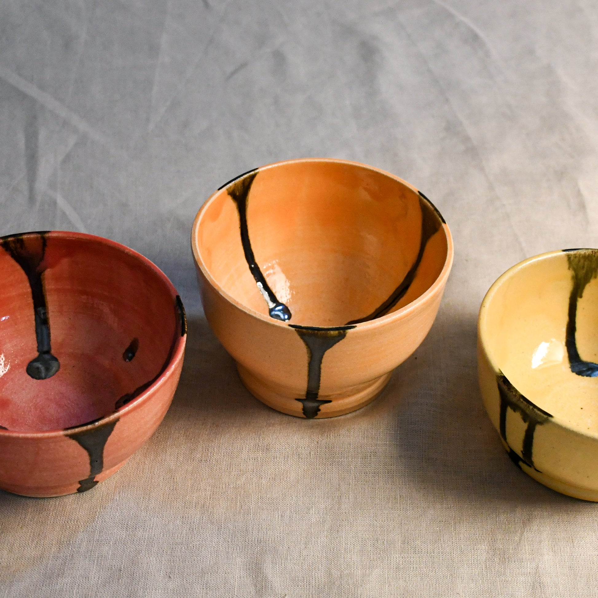 5th Buffalo soft finish chili bowls in coral, jack o lantern, and dandelion with black drips.
