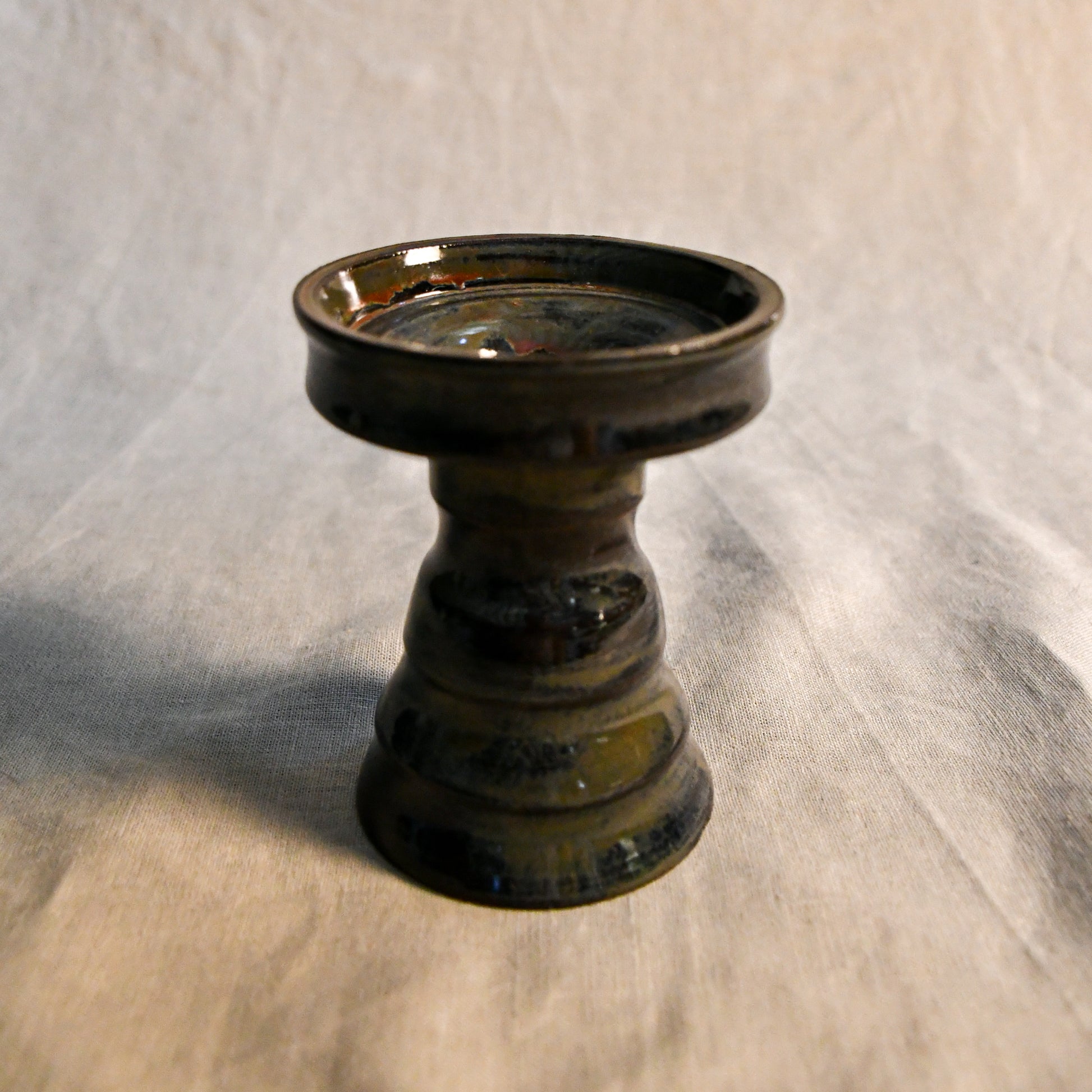 Handmade ceramic candlestick in Ancient Jasper glaze featuring a sculpted pedestal base and rich earthy tones of black, bronze, olive, and deep rust.
