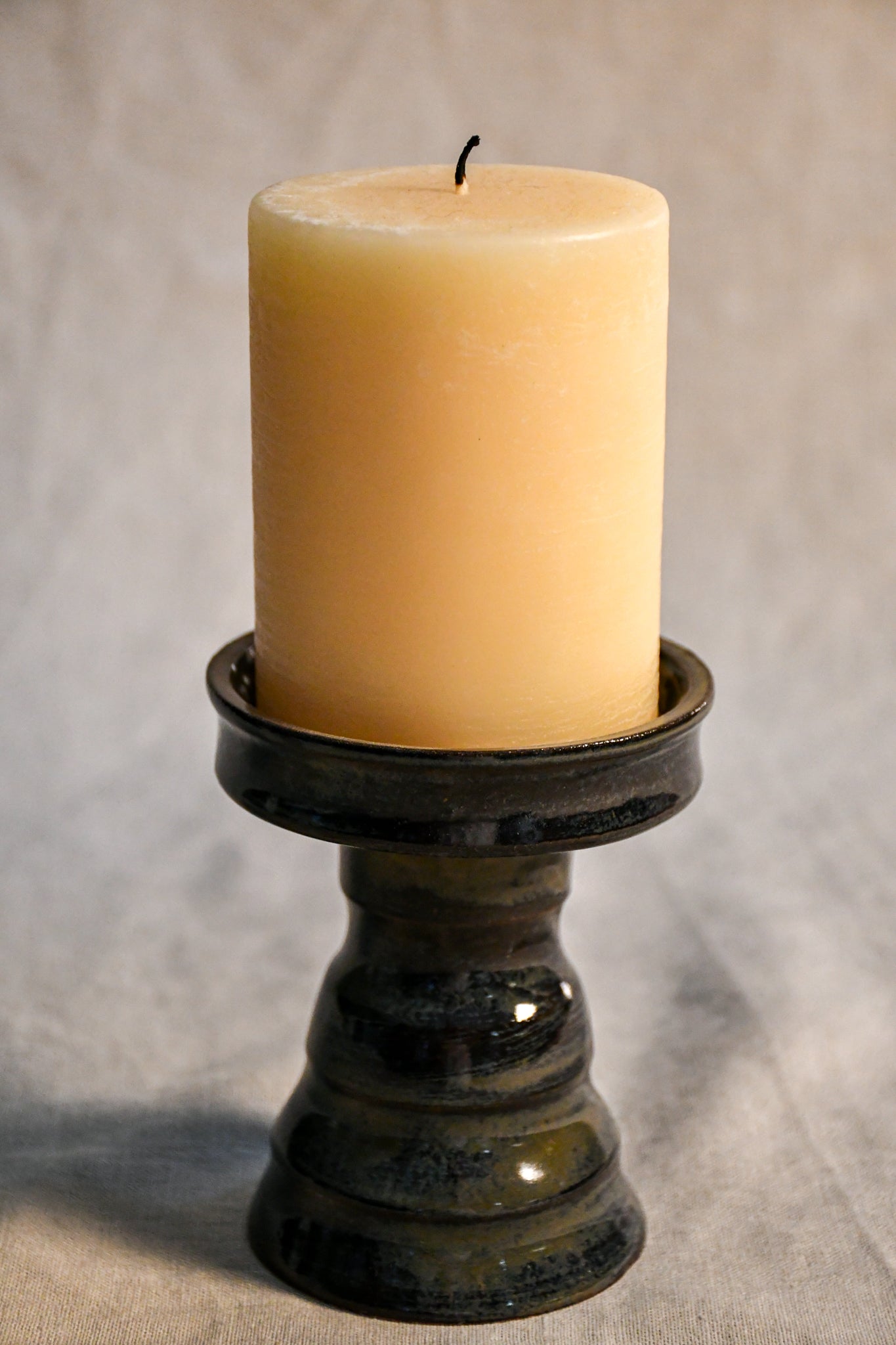 Handmade ceramic candlestick in Ancient Jasper glaze featuring a sculpted pedestal base and rich earthy tones of black, bronze, olive, and deep rust.