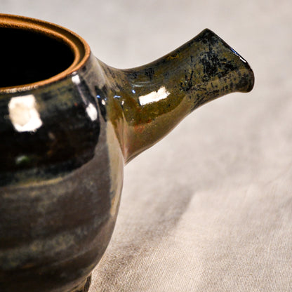 Close-up of the Ancient Jasper glaze on a handmade ceramic teapot, showcasing glossy layers of bronze, olive green, black, and deep rust tones.