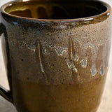 Handmade ceramic mug by Leigh Art featuring Espuela glaze with one-of-a-kind earth-tone movement and wheel-thrown craftsmanship.