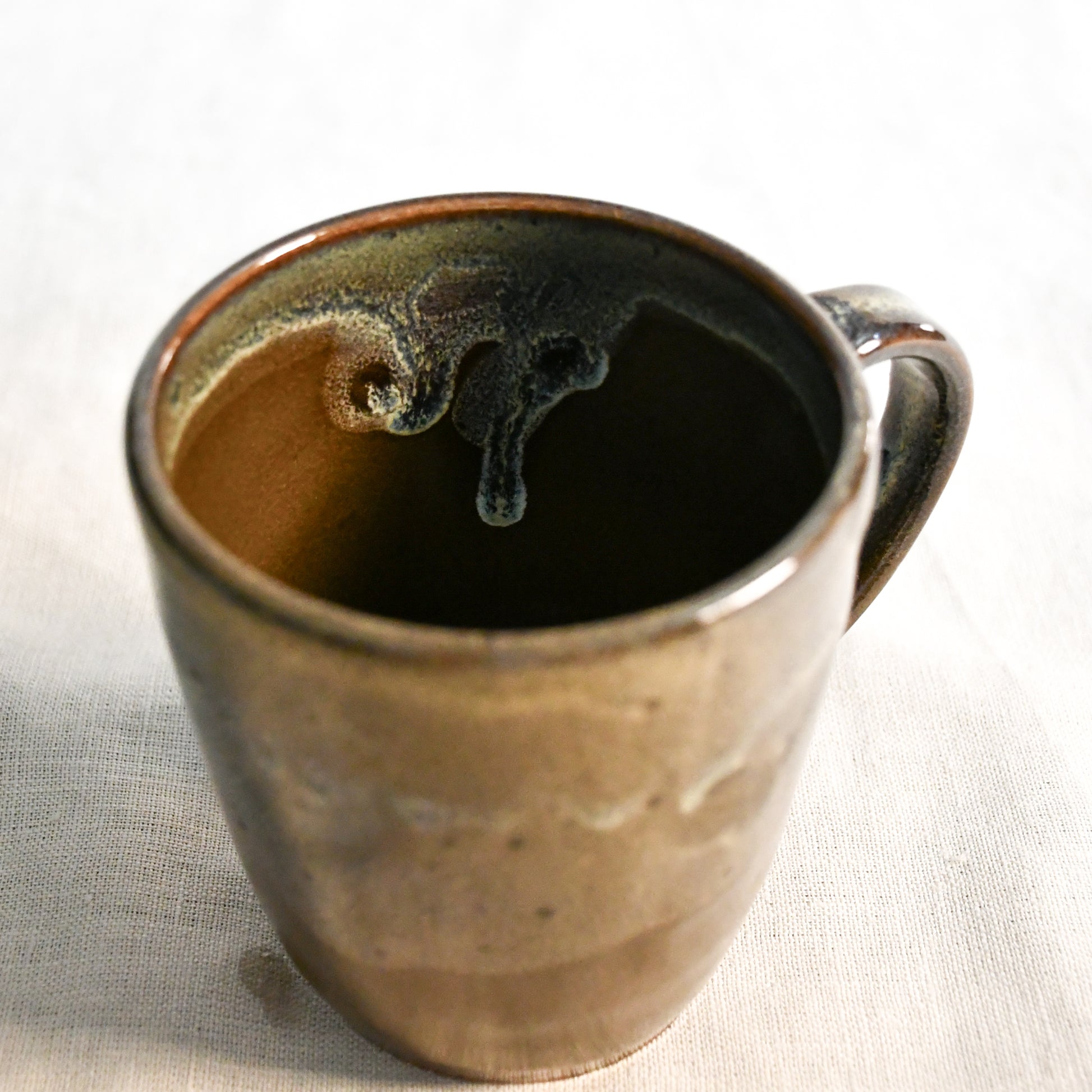 Handmade ceramic mug by Leigh Art featuring Espuela glaze with one-of-a-kind earth-tone movement and wheel-thrown craftsmanship.