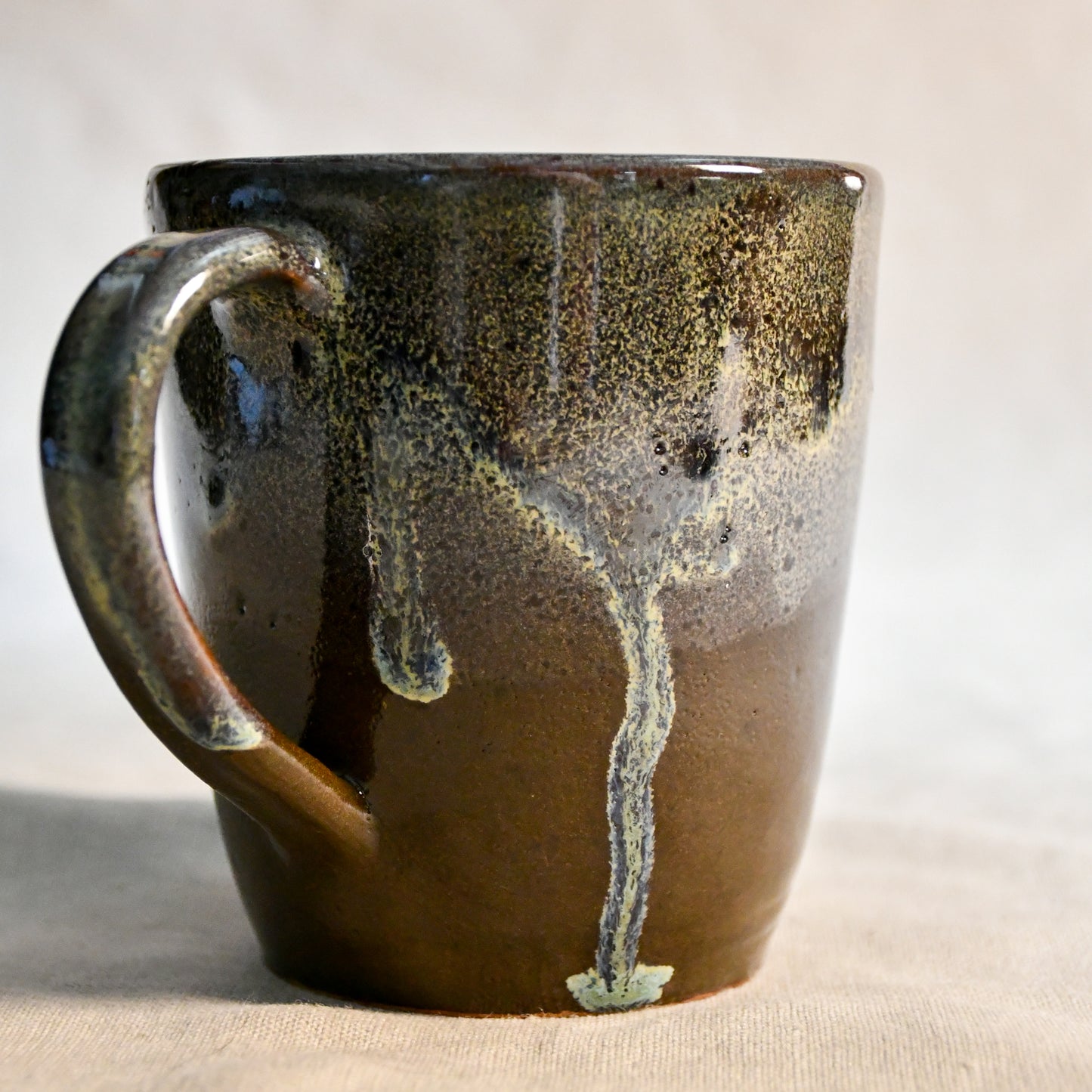 Handmade ceramic mug by Leigh Art featuring Espuela glaze with one-of-a-kind earth-tone movement and wheel-thrown craftsmanship.