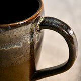 Handmade ceramic mug by Leigh Art featuring Espuela glaze with one-of-a-kind earth-tone movement and wheel-thrown craftsmanship.