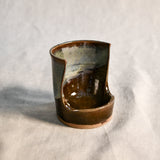 Handmade Espuela ceramic spoon rest by Leigh Art featuring layered earth-tone glaze with organic movement and one-of-a-kind variation.