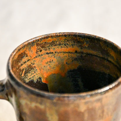 Close-up of the Ancient Jasper glaze inside a handmade stoneware mug, revealing ember orange and smoky black variations around the rim.