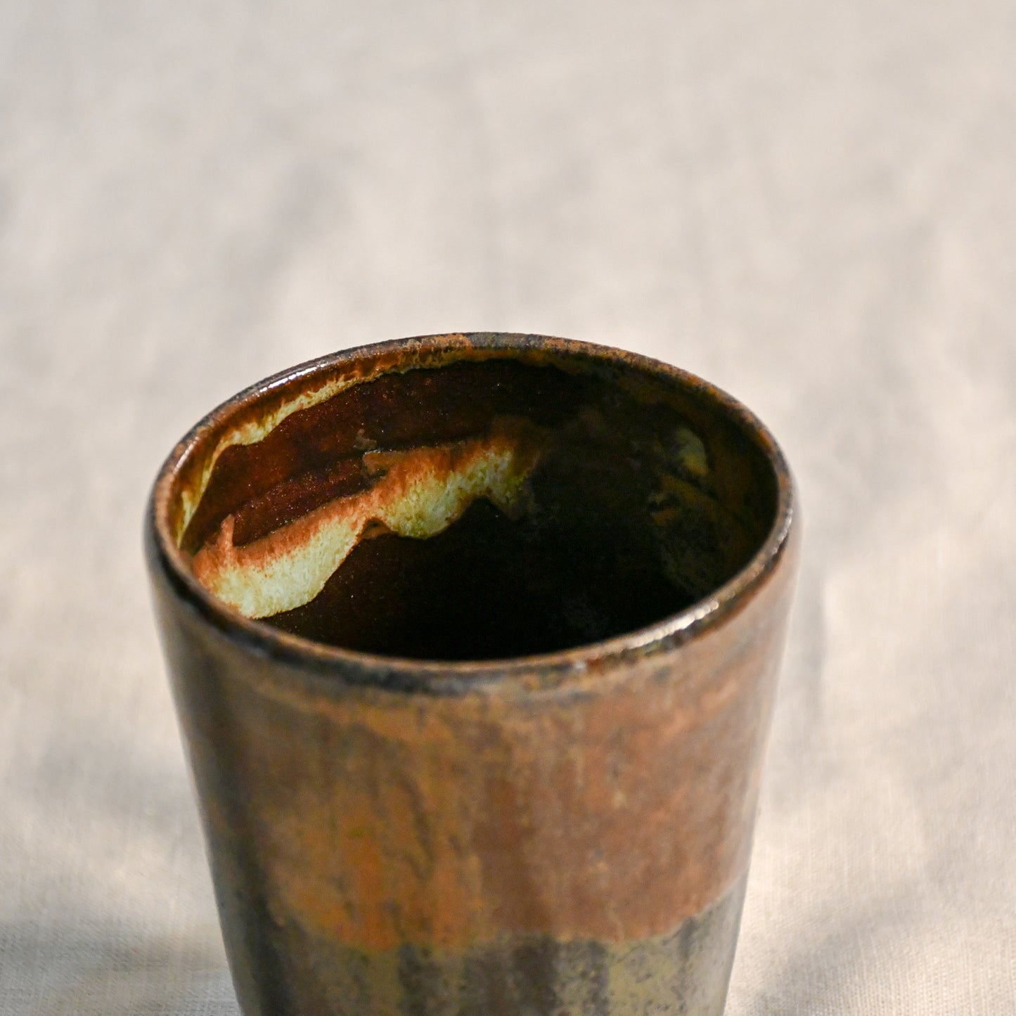 Close-up of the Ancient Jasper glaze inside a handmade stoneware mug, revealing ember orange and smoky black variations around the rim.