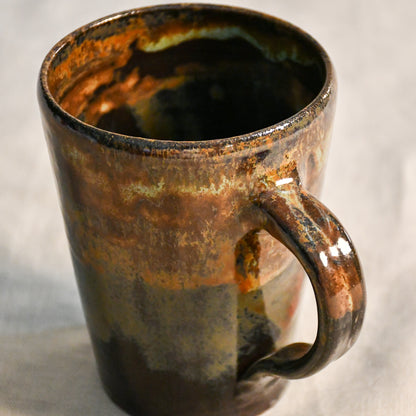 Handmade pottery mug with a comfortable hand-pulled handle and Ancient Jasper glaze in earthy black, rust, olive, and brown tones.