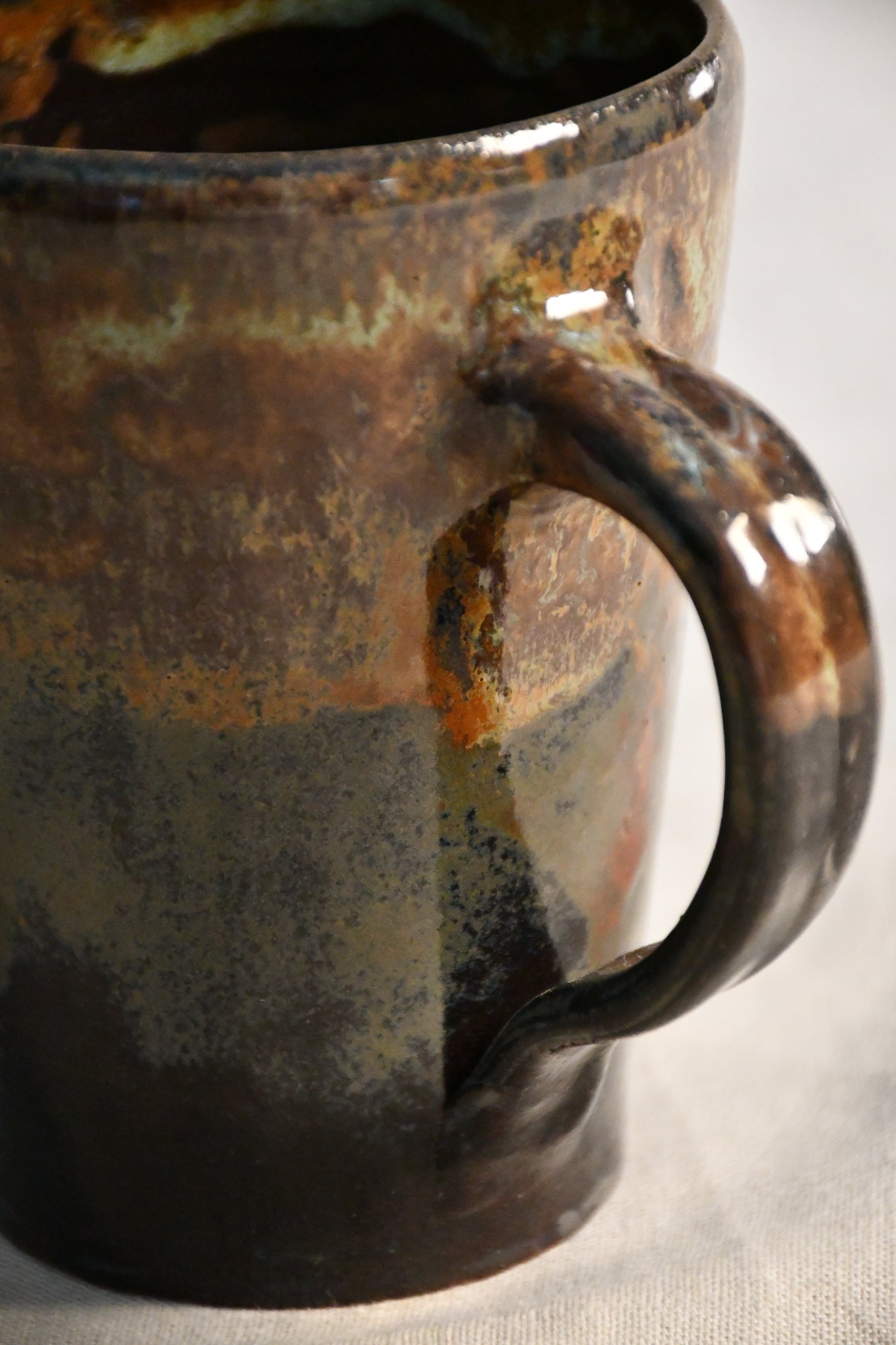 Handmade pottery mug with a comfortable hand-pulled handle and Ancient Jasper glaze in earthy black, rust, olive, and brown tones.