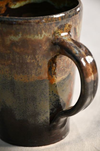 Handmade pottery mug with a comfortable hand-pulled handle and Ancient Jasper glaze in earthy black, rust, olive, and brown tones.