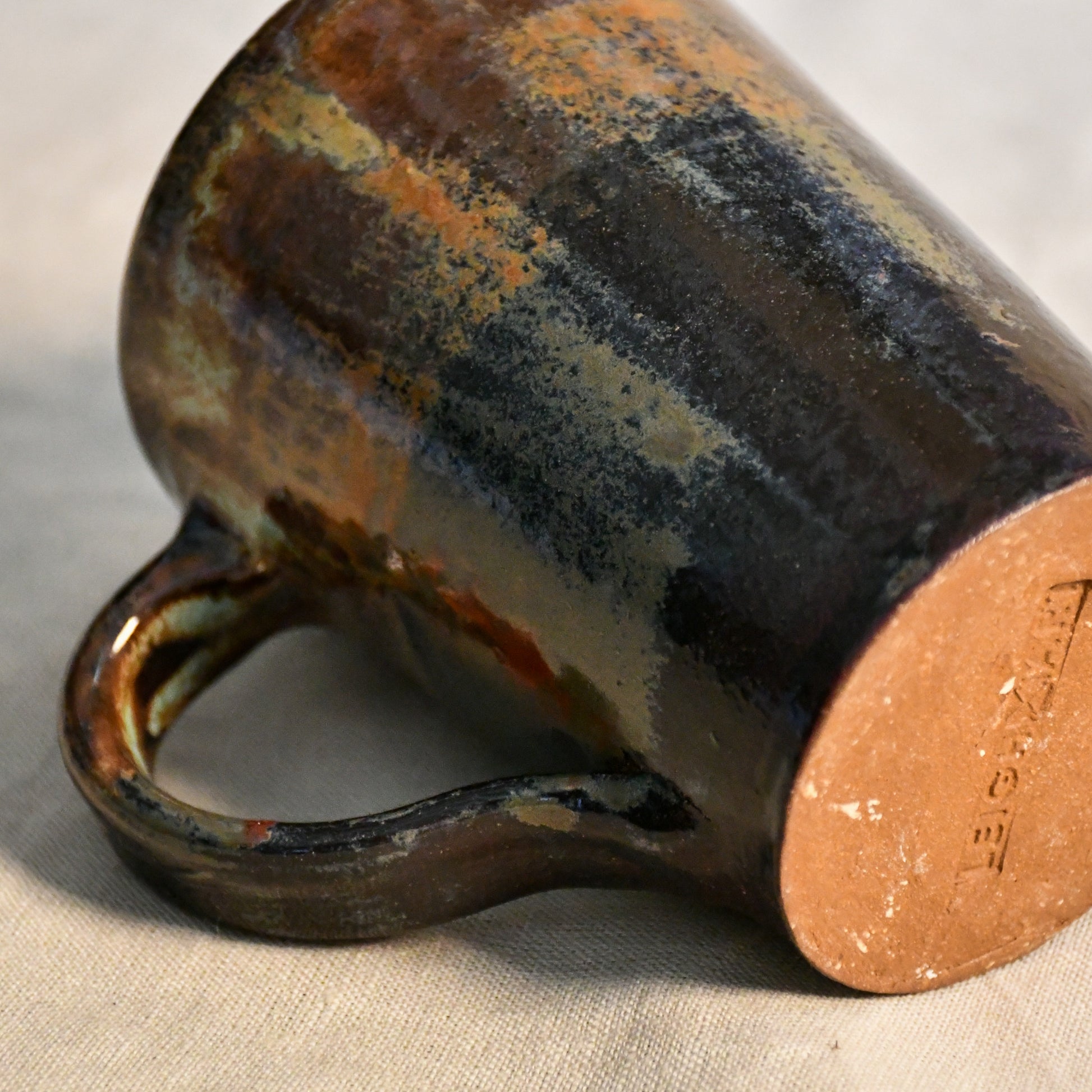 Detailed view of the Ancient Jasper glaze on a handcrafted ceramic mug, showcasing organic rust, olive, charcoal, and brown textures.