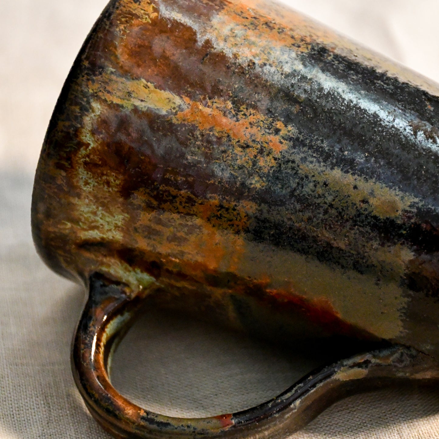 Detailed view of the Ancient Jasper glaze on a handcrafted ceramic mug, showcasing organic rust, olive, charcoal, and brown textures.