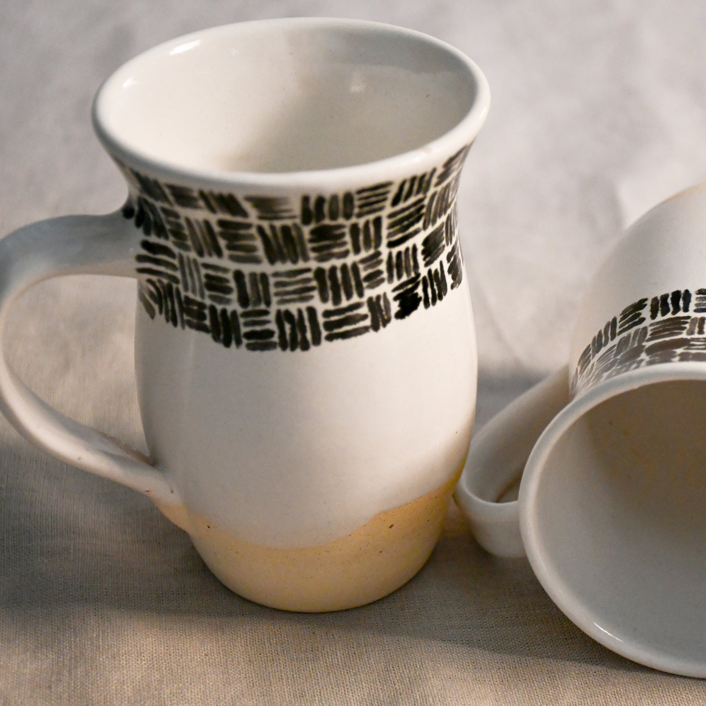 Handmade ceramic mugs with glossy white interiors and softly flared rims designed for everyday use.