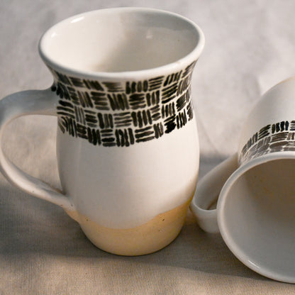 Handmade ceramic mugs with glossy white interiors and softly flared rims designed for everyday use.