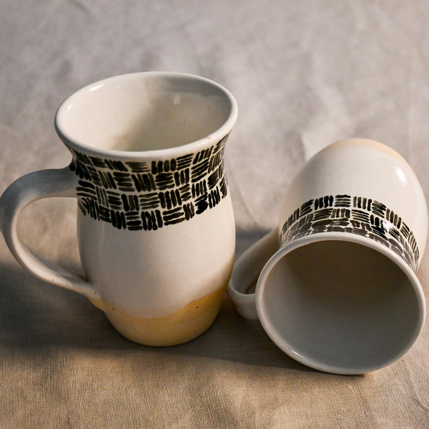 Handmade ceramic mugs with glossy white interiors and softly flared rims designed for everyday use.
