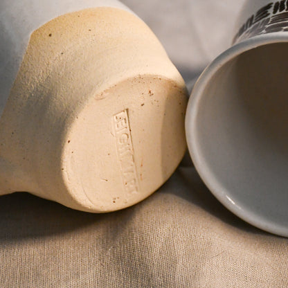 Underside of a handmade pottery mug featuring the Leigh Art maker's mark impressed into the unglazed clay foot.