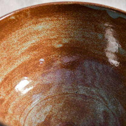 Close-up of the Heirloom Blue glaze inside a handmade ceramic chili bowl, showcasing layered rust, chestnut, and blue-green variation created during firing.