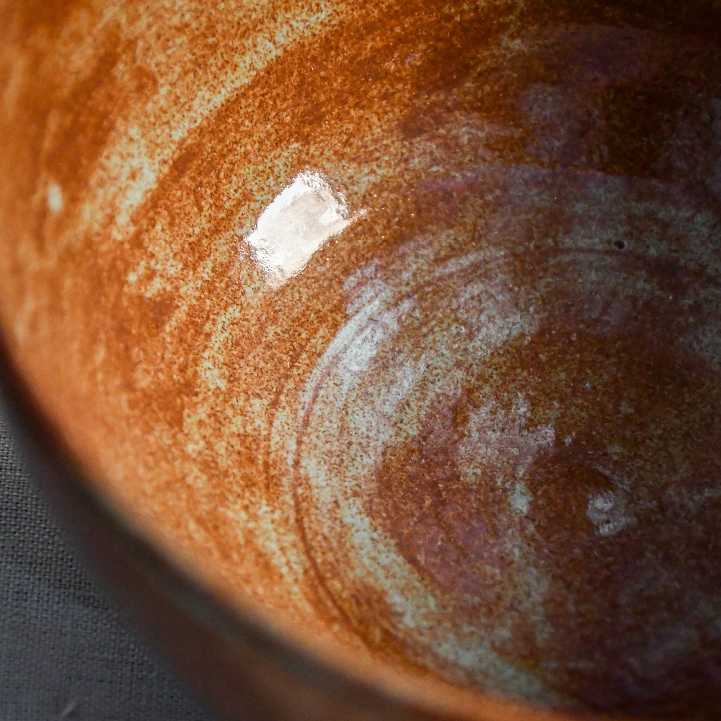 Close-up of the Heirloom Blue glaze inside a handmade ceramic chili bowl, showcasing layered rust, chestnut, and blue-green variation created during firing.