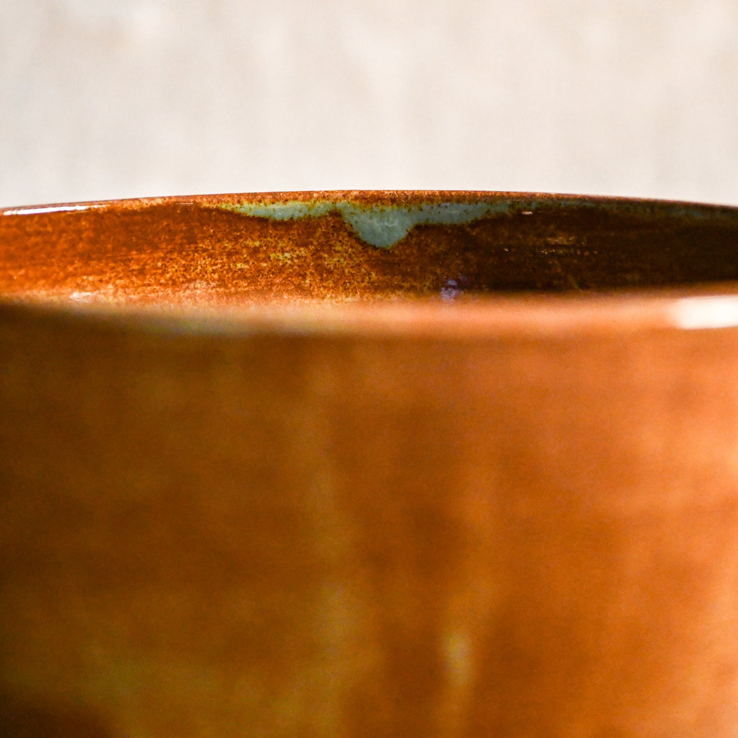 Close-up of the rim of a wheel-thrown ceramic chili bowl featuring Heirloom Blue glaze with blue-green accents and warm earthy tones.