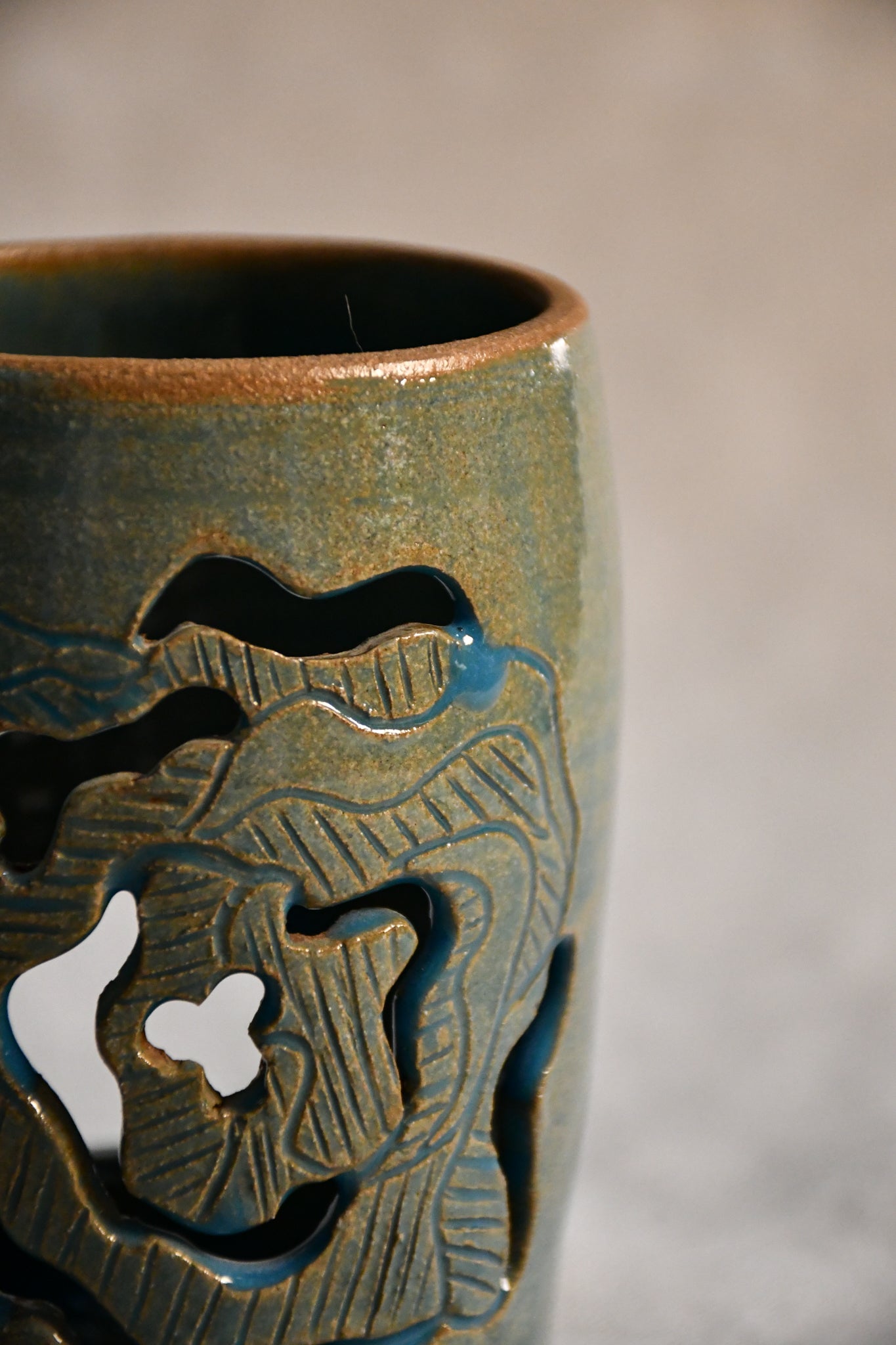 Close up of wheelthrown ceramic lantern, hand carved Peony design and glazed in turquoise. 