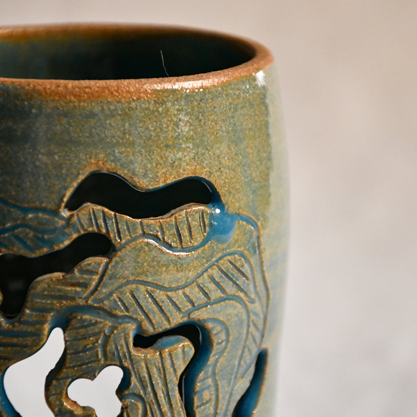 Close up of wheel thrown ceramic lantern, hand carved Peony design and glazed in turquoise. 