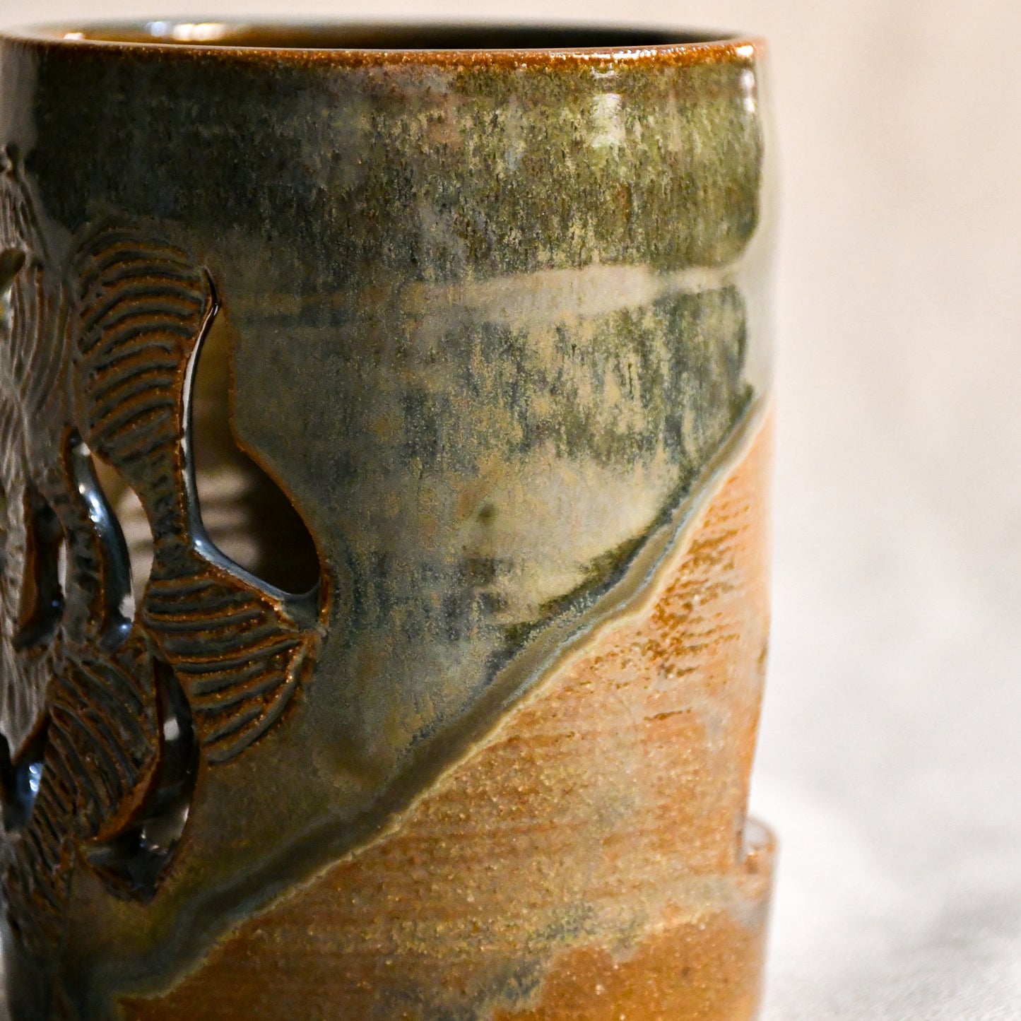 Close up of wheel thrown ceramic lantern, hand carved Peony design and glazed in Gun Metal Green. 