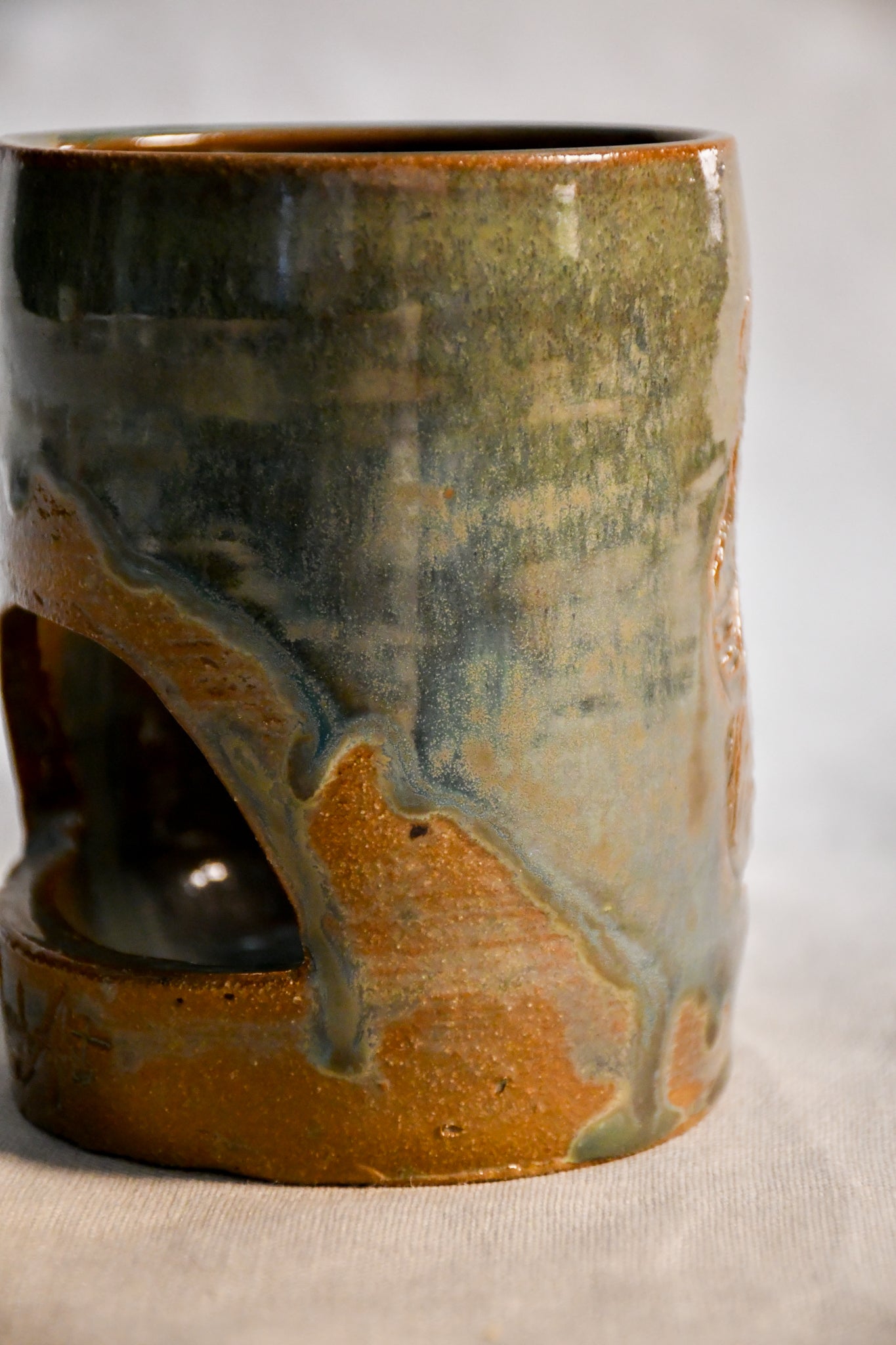 Close up of wheel thrown ceramic lantern, hand carved Peony design and glazed in Gun Metal Green. 