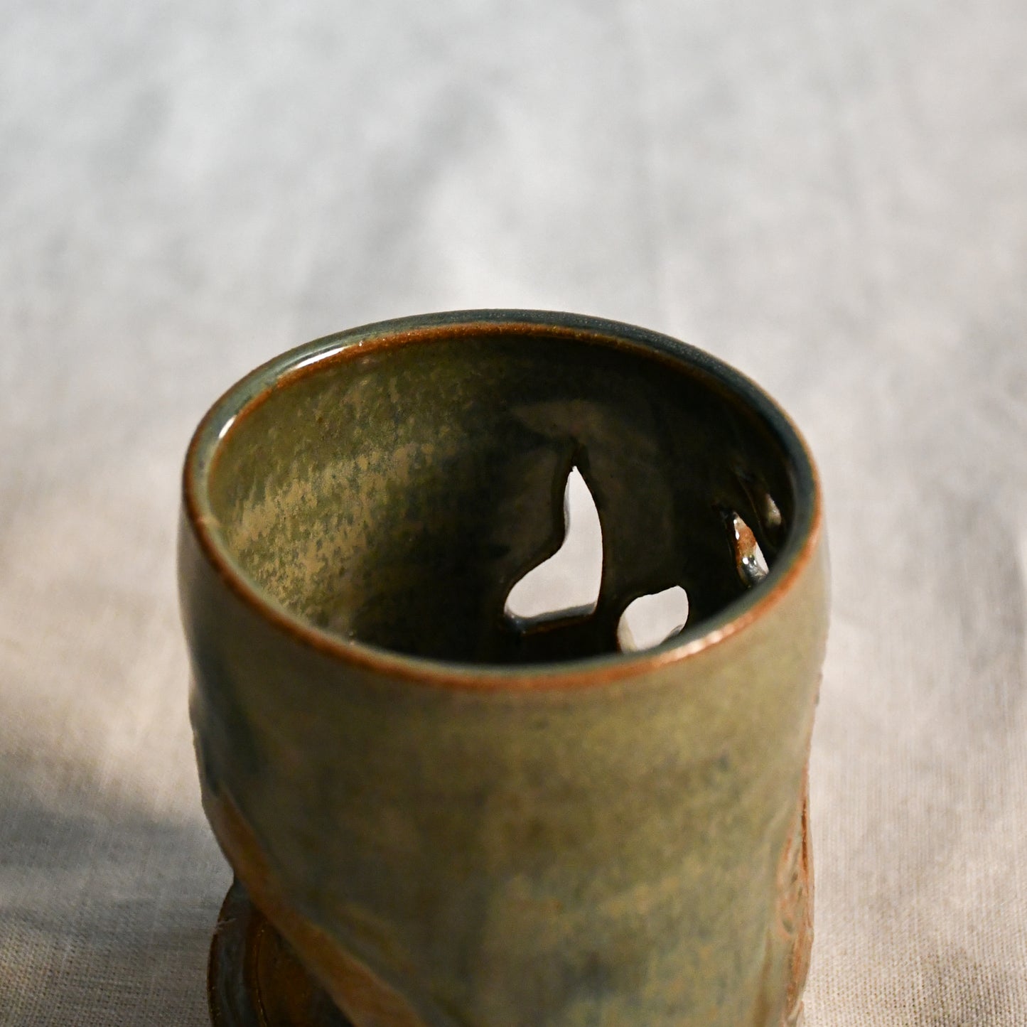 Close up of wheel thrown ceramic lantern, hand carved Peony design and glazed in Gun Metal Green. 