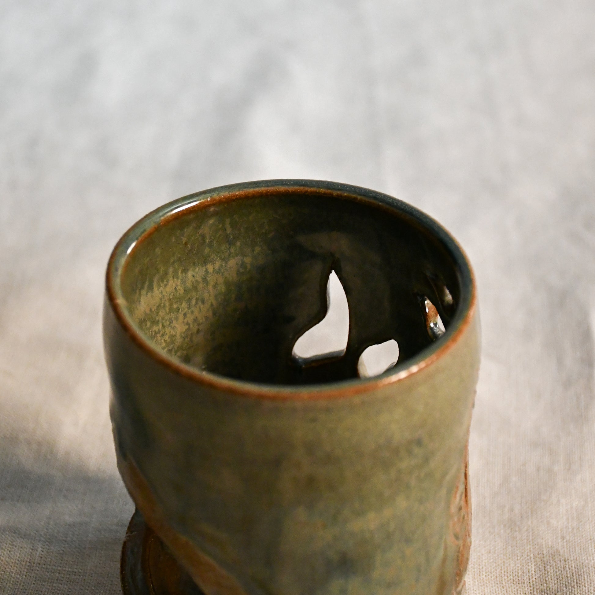 Close up of wheel thrown ceramic lantern, hand carved Peony design and glazed in Gun Metal Green. 