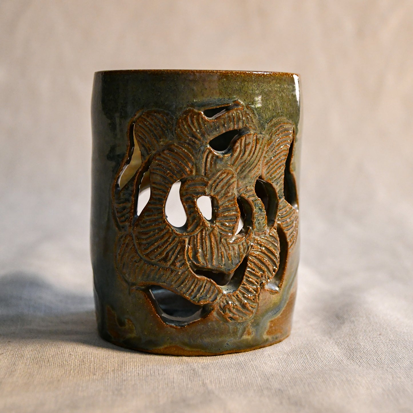 Close up of wheel thrown ceramic lantern, hand carved Peony design and glazed in Gun Metal Green. 