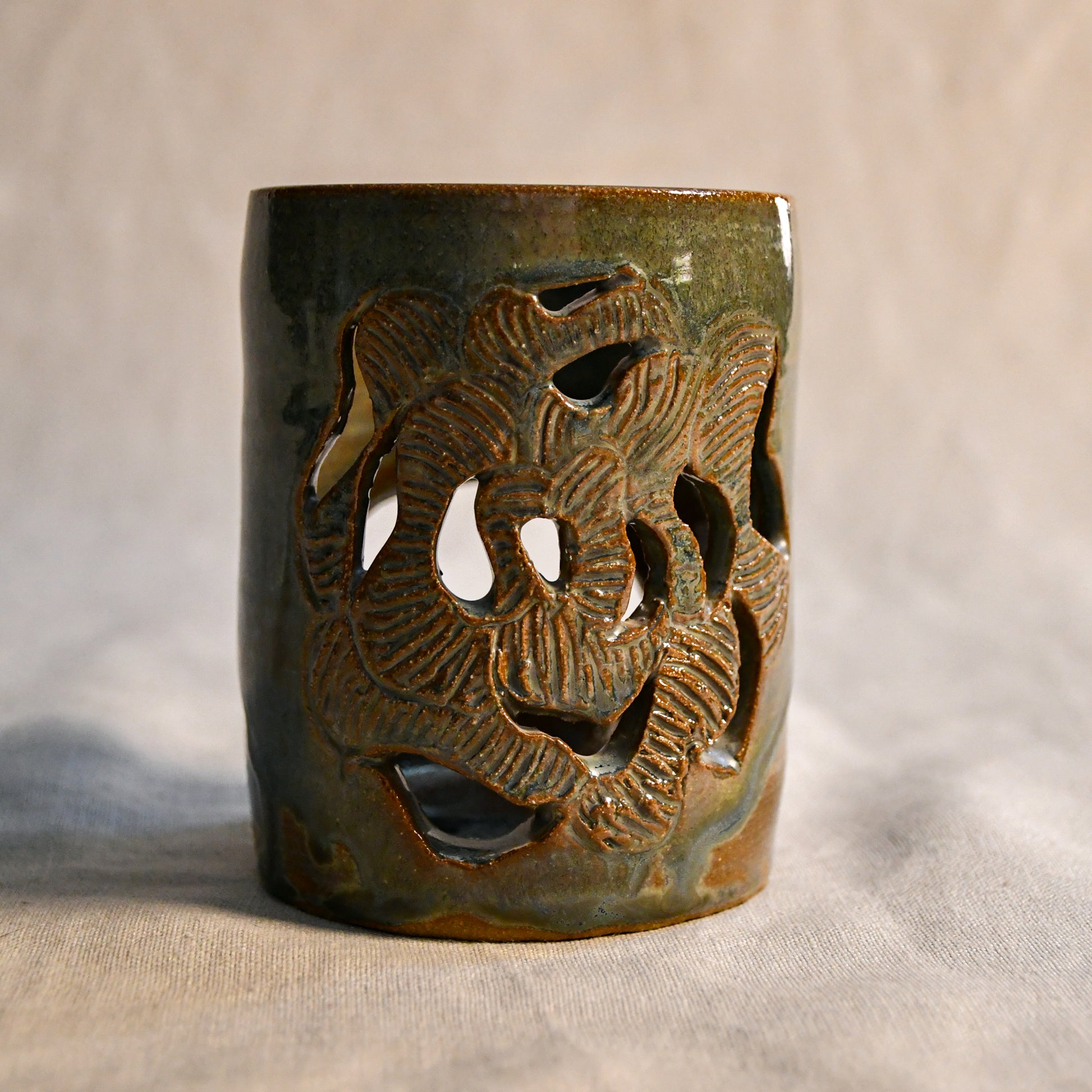 Close up of wheel thrown ceramic lantern, hand carved Peony design and glazed in Gun Metal Green. 