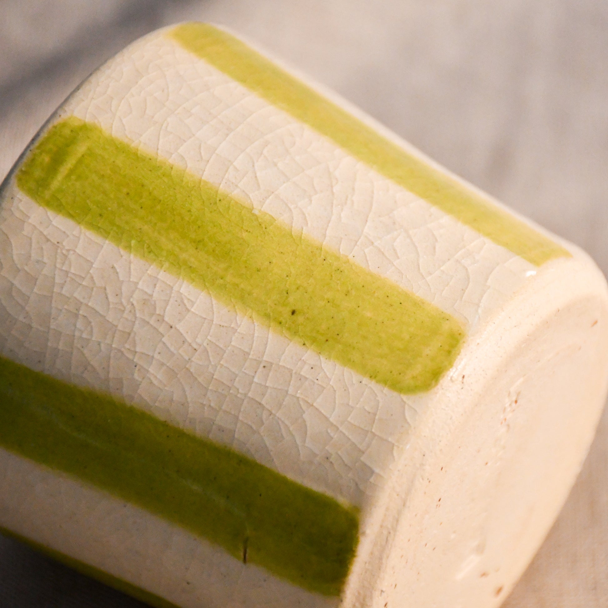 Detail of the lime striped mini mug featuring hand-painted stripes and fine crazing beneath the glossy clear glaze.