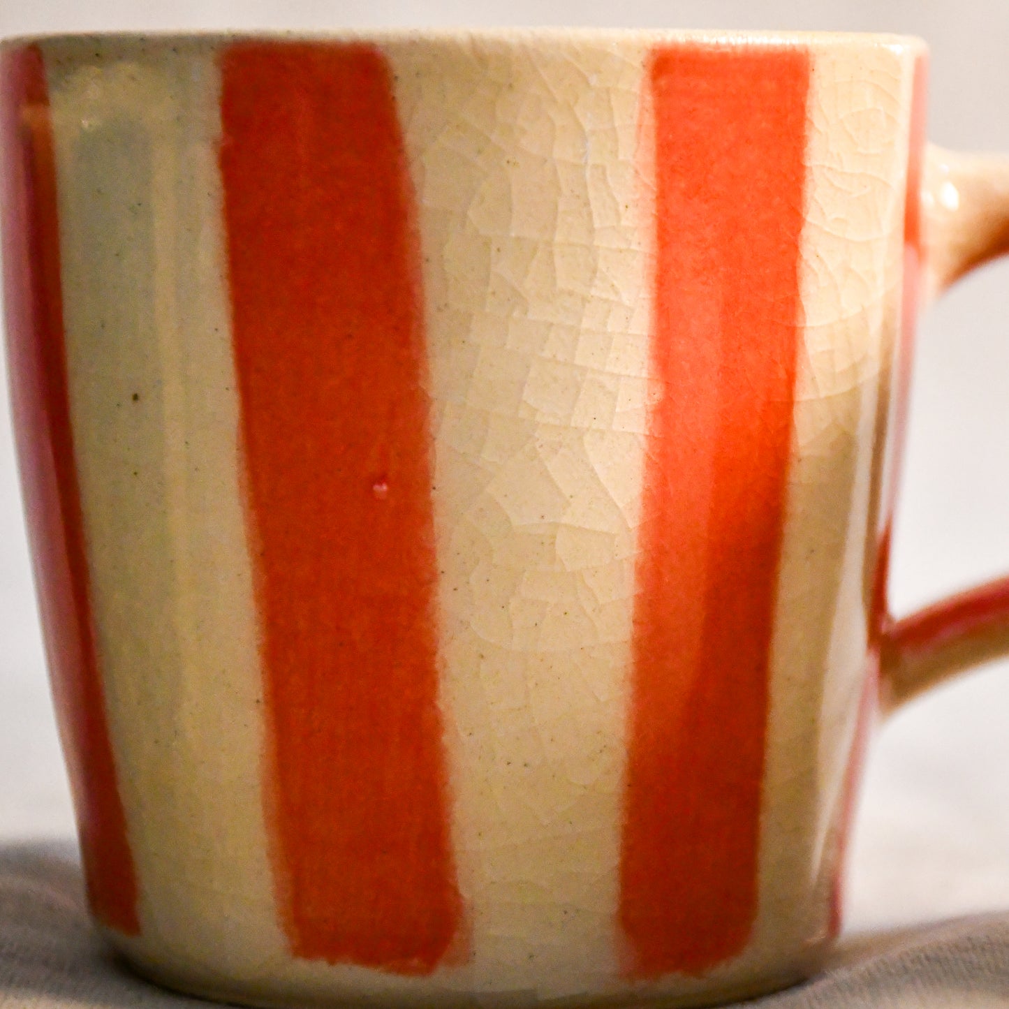 Close-up of the coral striped mini mug highlighting the organic crackle pattern created by the clear glaze.