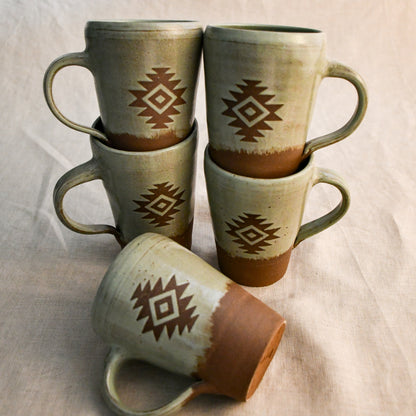 Five handmade Wild Rojo pottery mugs featuring an Aztec-inspired design in earthy green glaze, stacked together to showcase the coordinating mug pack.